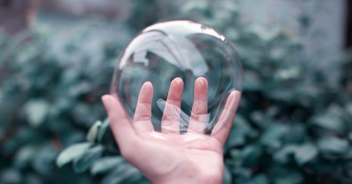 hand holding large soap bubble like fragile housing bubble