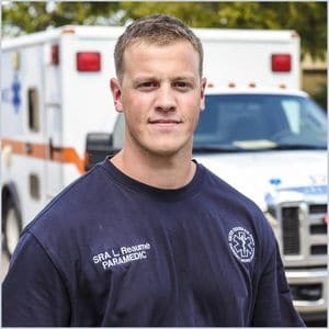Male paramedic standing next to an ambulance