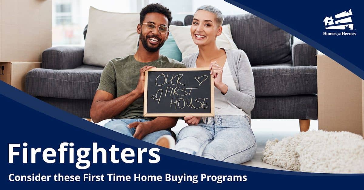 man woman couple sitting on floor in front of couch with moving boxes holding sign firefighter first time home buyer Homes for Heroes