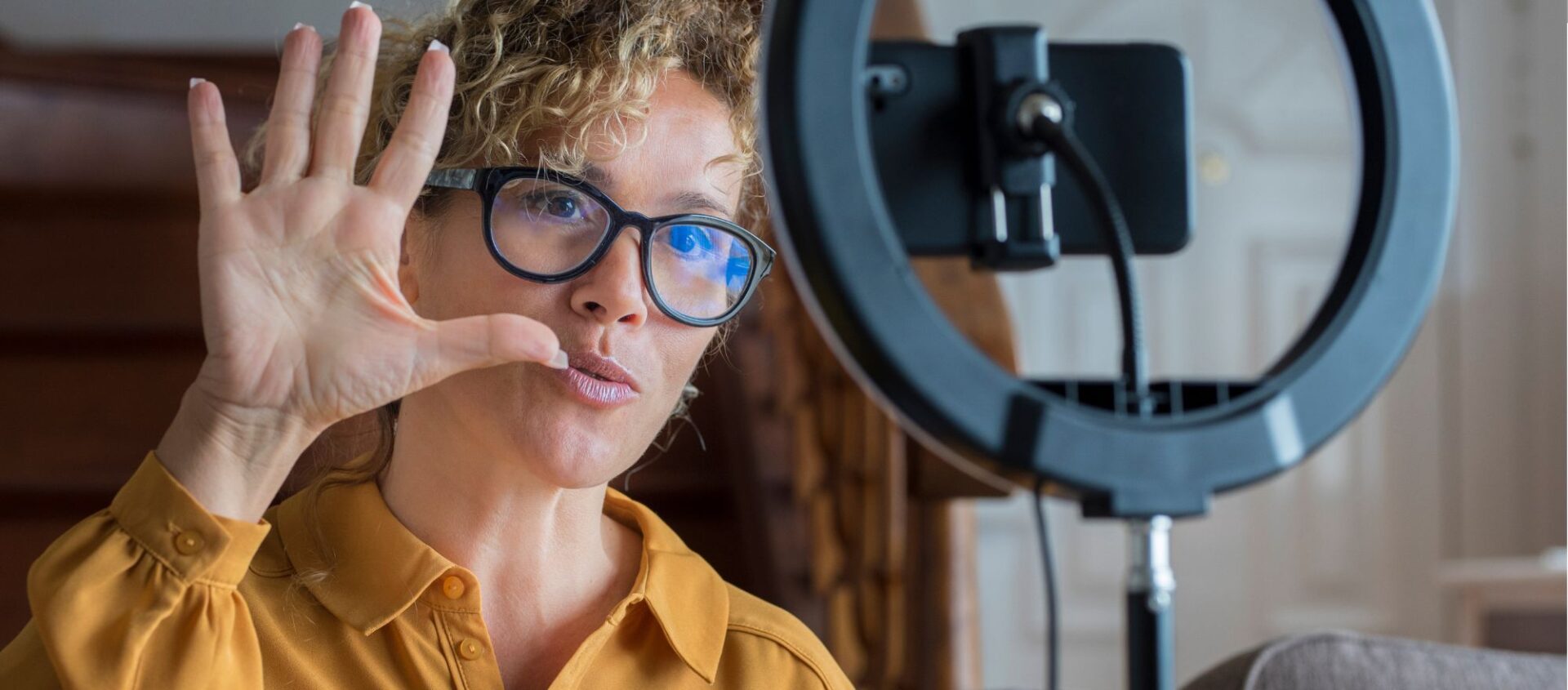 female real estate agent wearing glasses holding up five fingers in home recording real estate videos for social media followers